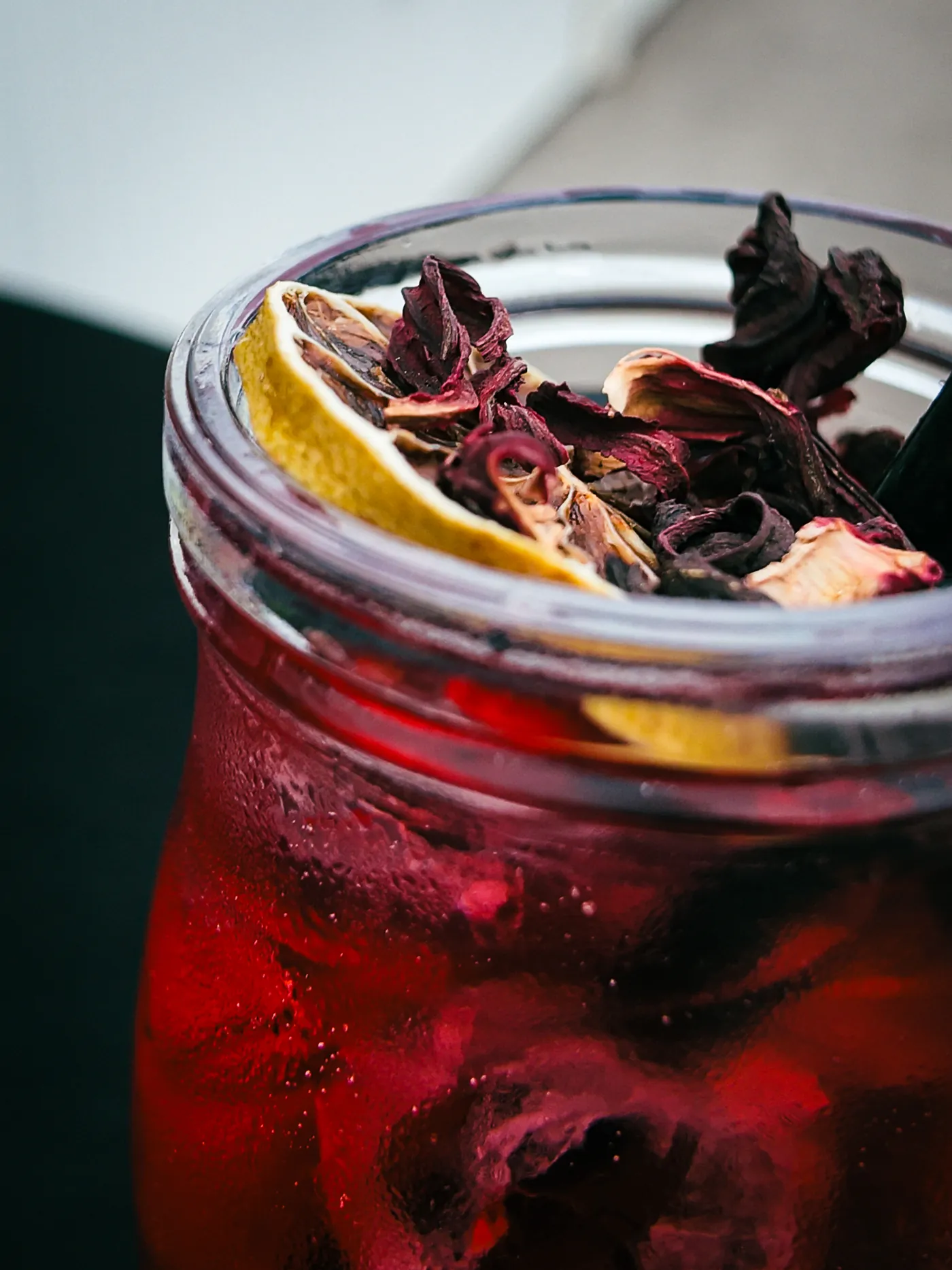 Hibiskus-Limonade im Glas mit getrockneter Zitrone und Blüten