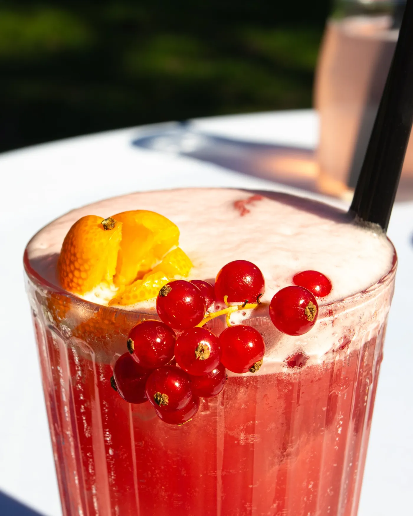 Roter Cocktail mit Schaumkrone, Johannisbeeren und Kumquat