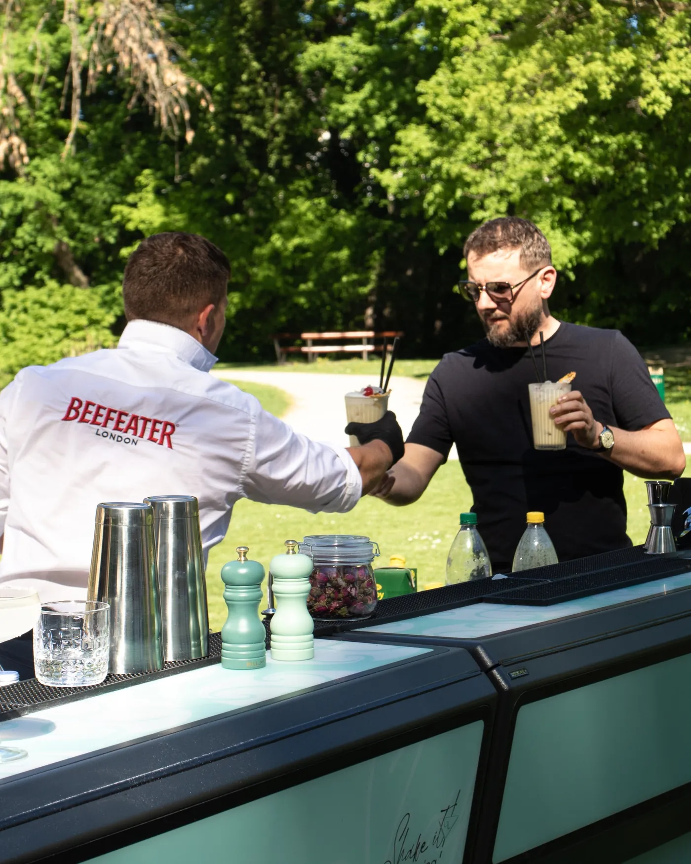 Die mobile Shake it! Bar im Park, Barkeeper reicht Cocktails über die Theke