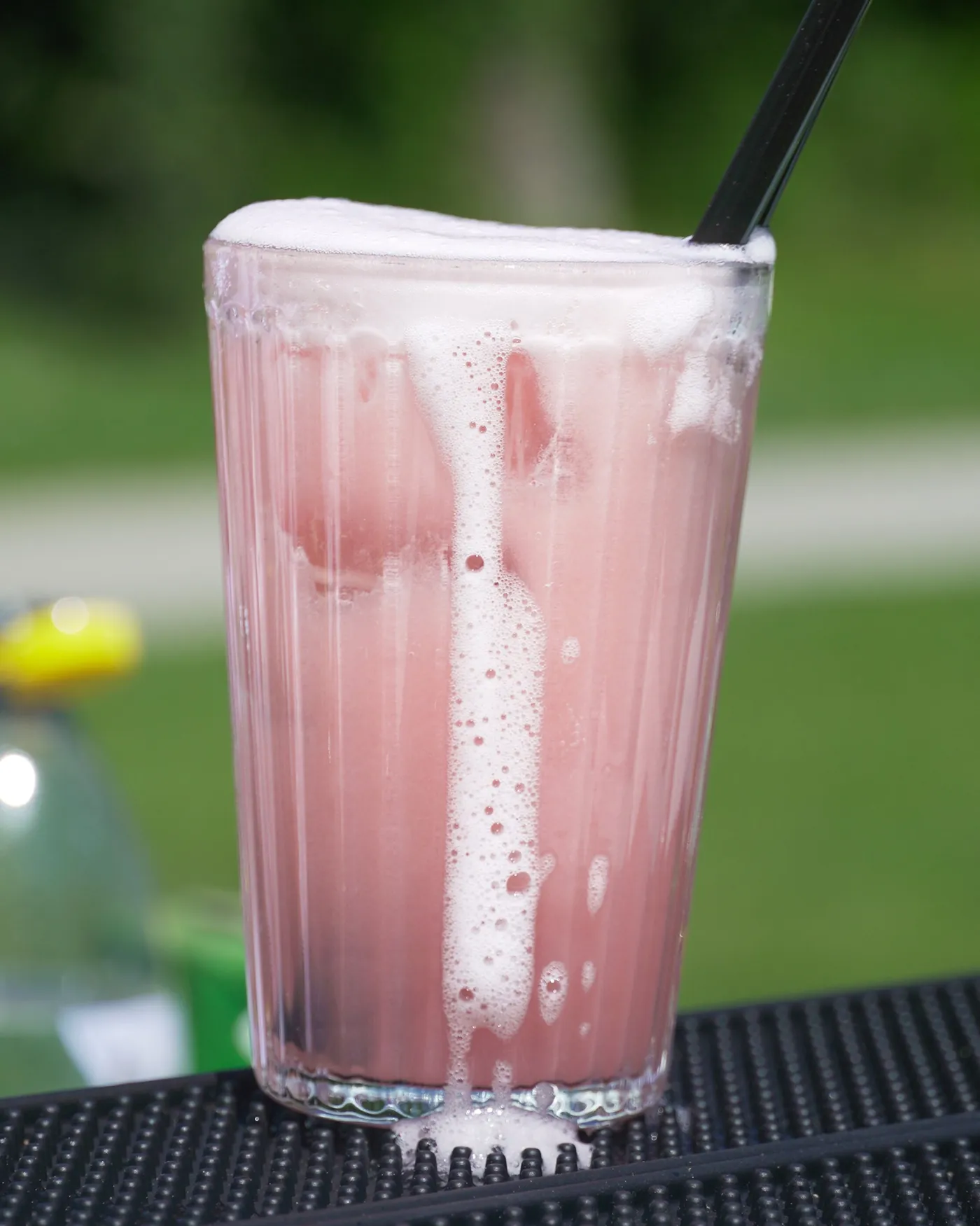 Rosafarbener Fizz mit Schaumkrone auf der Barmatte