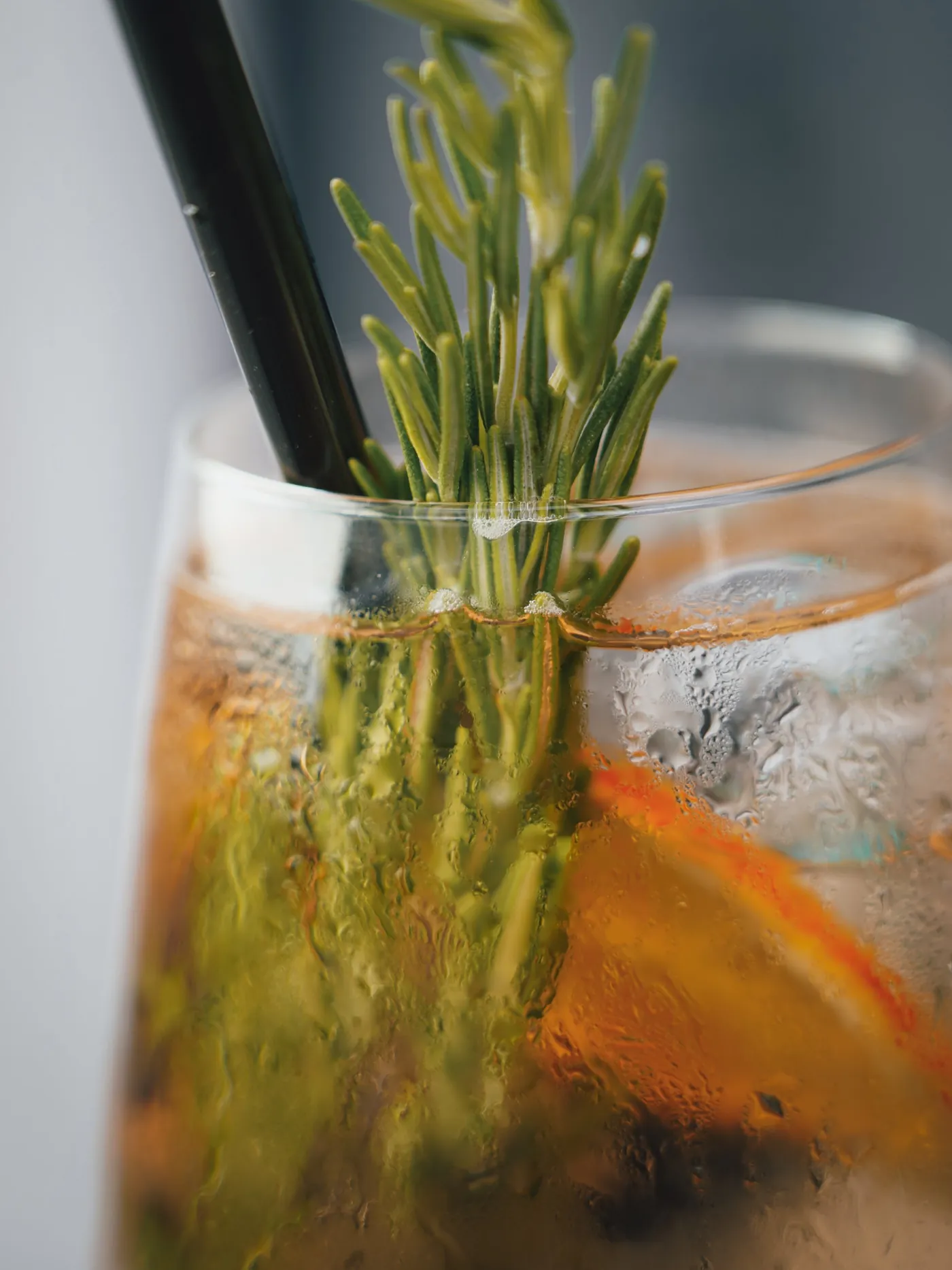 Longdrink mit Rosmarinzweig und Orangenscheibe