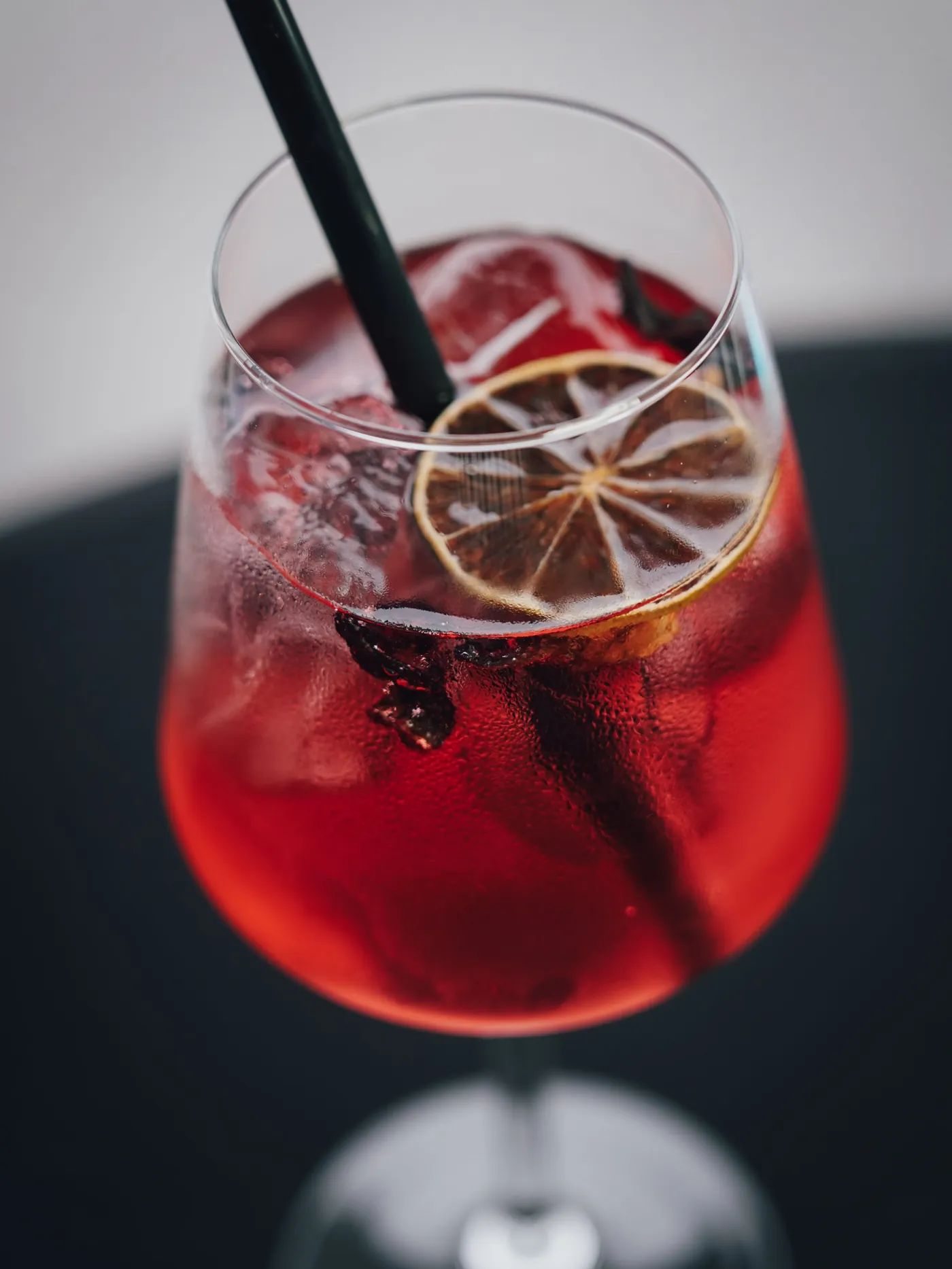 Roter Spritz im Weinglas mit getrockneter Limette
