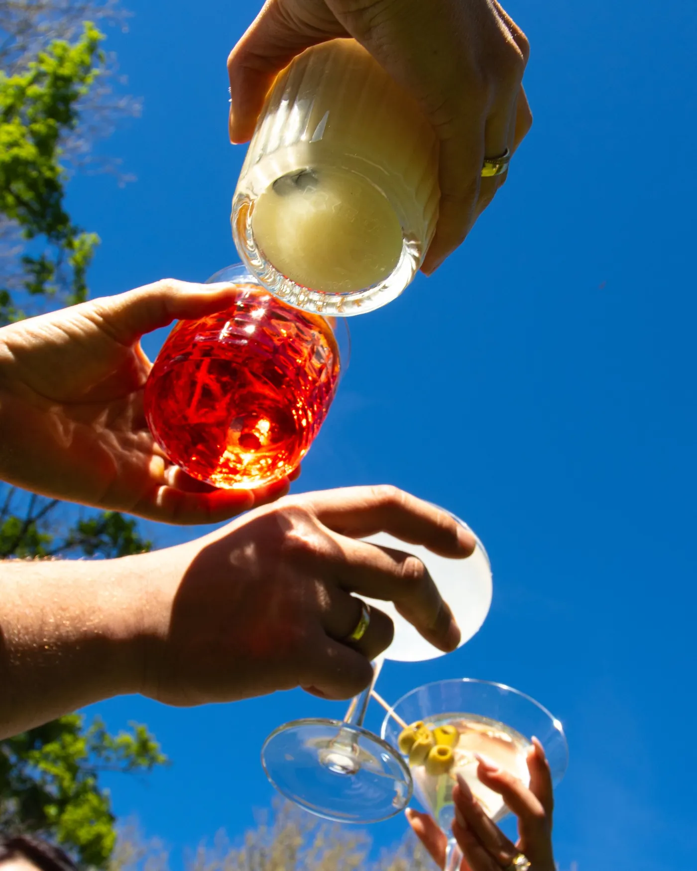 Gäste stoßen mit Cocktails unter blauem Himmel an